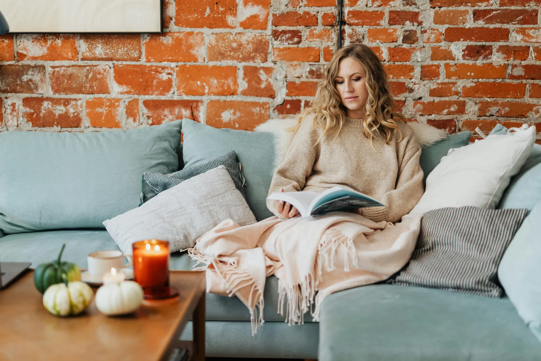 Femme hiver Une femme lit, blottie sous un plaid sur son canapé