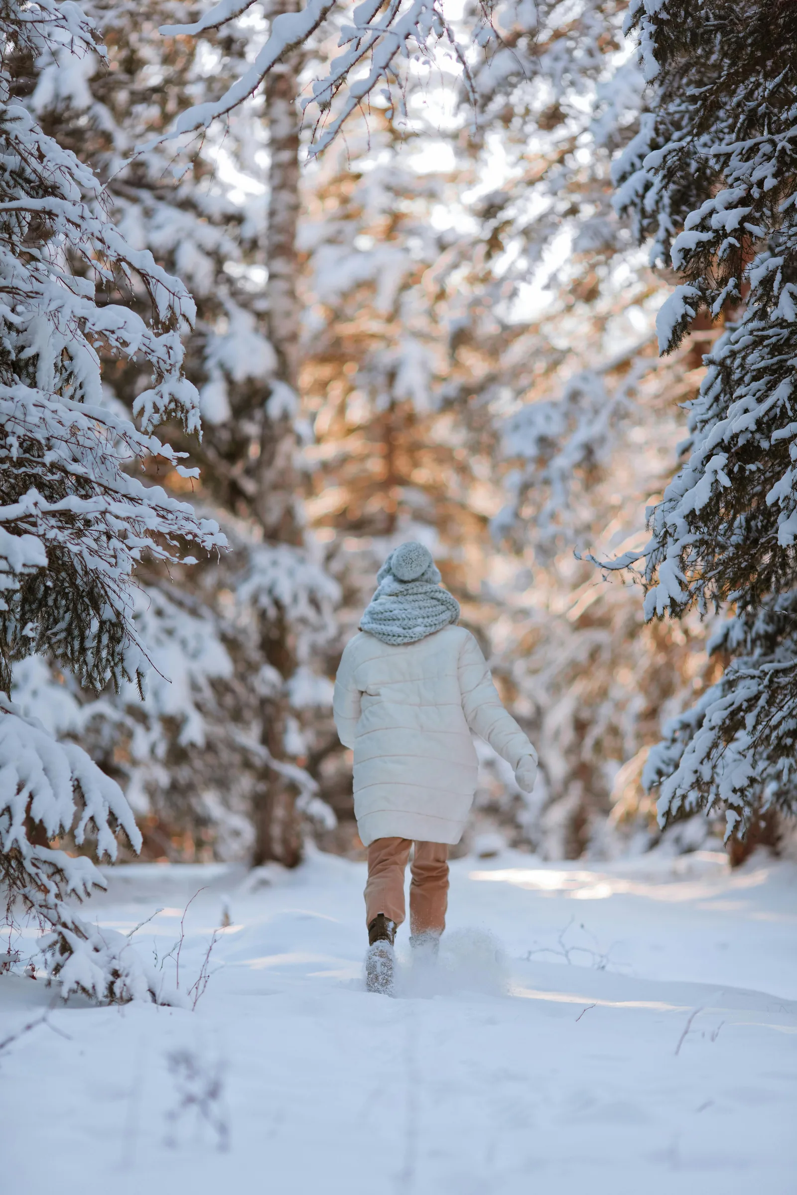 une personne marche dans une forêt enneigée